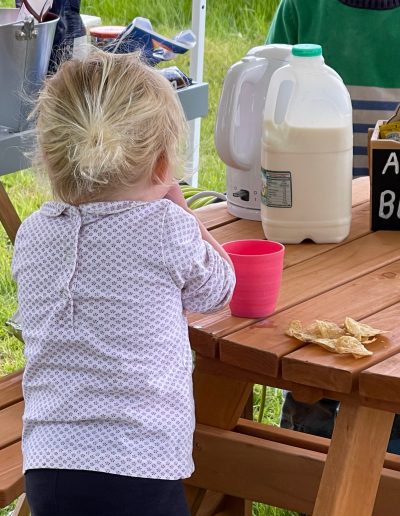 A young child has a snack at a picnic table