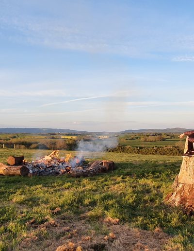 Two people relaxing on the large tree stump next to the firepit